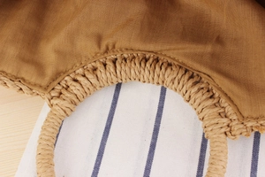 Detail of paper straw woven bag featuring integrated round handle and brown fabric lining