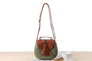 Dettaglio della borsa rotonda verde intrecciata con finiture in pelle marrone e nappa