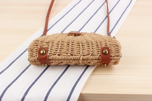 Detailed shot of handmade woven paper straw bag with brown leather trim and metal rivets