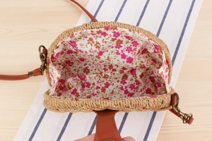Detail view of woven paper rope bag featuring floral cotton lining and leather strap