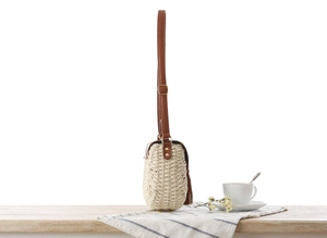 Dettaglio borsa in paglia di carta intrecciata con tracolla in pelle e rivetti metallici