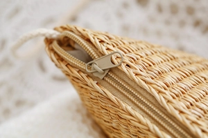 Détails de la texture du sac en paille tressée et fermeture éclair en métal lisse