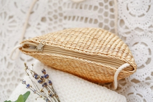 Vue détaillée du sac en paille fait main avec fermeture éclair sur dentelle blanche
