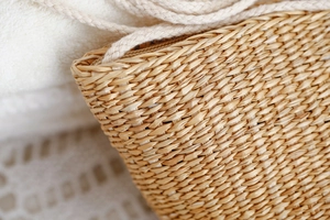 Gros plan sur la texture de paille tressée et la poignée en corde de ce sac de plage d'été