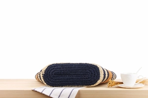 Detailed bottom view of a multi-color striped woven straw bag on a wooden table