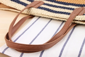 Detail of striped woven shoulder bag featuring beige blue fibers and brown leather handle