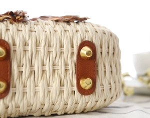 Dettaglio borsa in corda di carta intrecciata con nappe in pelle e borchie dorate