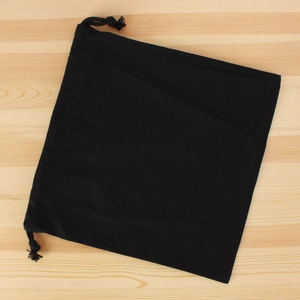 Flat lay of a square black canvas drawstring organizer bag on a light wood surface