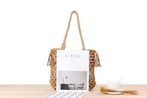 Detailed close-up of handmade woven mesh beach bag with decorative side tassels