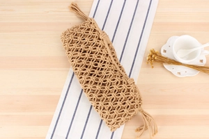 Detail of hand-woven cotton rope beach bag with tassel fringe on a wooden table