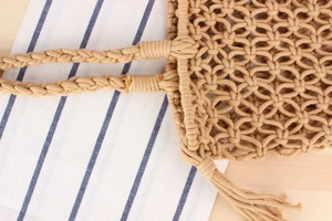 Detail of handmade woven cotton shoulder bag featuring hollow mesh and tassel accents