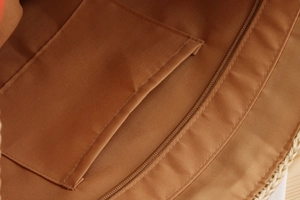 Detail view of woven beach bag interior featuring a brown lining with an inner pocket and zipper