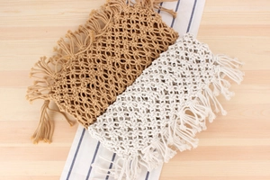 Detail of bohemian handmade woven bags with net texture and long tassels on wood
