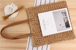 Detail of woven paper rope tote bag featuring leather shoulder straps and zip closure