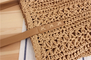 Close-up of hollow star weave pattern and stitched leather strap on straw bag