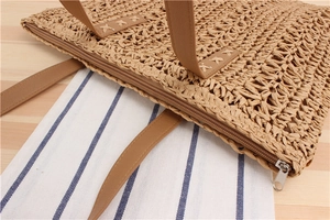 Close-up of paper rope woven bag showing the secure brown leather handle and zipper detail