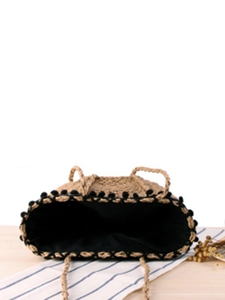 Minimalist straw woven beach tote with black pom-pom trim and fabric lining
