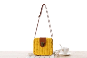 Nahaufnahme der gelben Strohtasche mit brauner Lederklappe und Retro-Metallverschluss