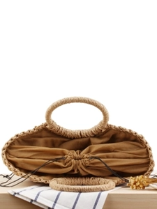 Handwoven straw tote bag with drawstring inner pouch on a rustic wooden table for summer