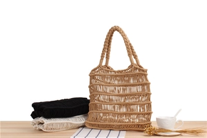 Detail of three colors of handmade cotton rope mesh tote bags on a wooden surface