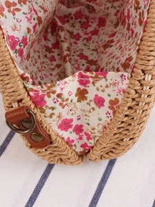 Handwoven semicircular straw beach bag featuring floral lining and leather accents