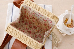 Detail der Stroh-Umhängetasche mit rosa Blumenfutter und Leder-Schultergurt