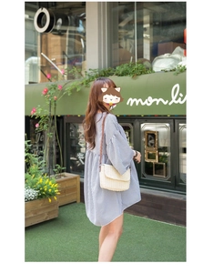 Detail of a beige woven rectangle crossbody bag paired with a blue gingham puff sleeve dress