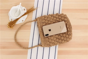 Close-up of brown hand-woven straw bucket bag with floral texture and phone size reference