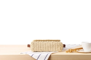Detailed texture of hand-woven straw crossbody bag with brown leather strap attachments