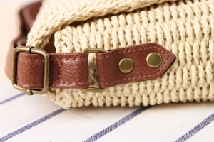 Close-up of handmade woven texture with brown leather strap and bronze metal buckle