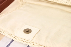 Detailed macro view of beige woven bag with magnetic snap closure and cotton lining