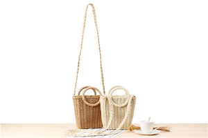Detail of paper rope woven bucket bags in brown and white with round handles for summer vacations