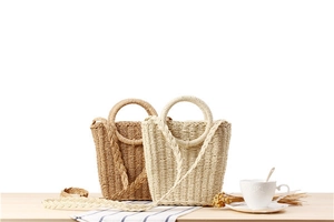 Detail of hand-woven paper rope beach bags in beige and brown with round handles