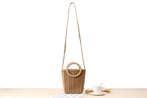 Detailed close-up of handmade paper rope woven bag with round handles on wooden surface