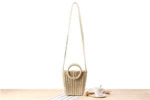 Close-up of a woven paper rope bucket bag with round handles on a wooden table