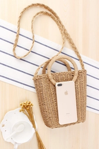 Detailed overhead view of a woven paper rope beach bag with handles and a long shoulder strap
