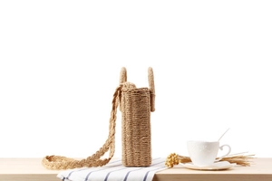 Close-up of woven paper rope bag with circular handles and rustic braided shoulder strap