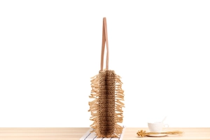 Close-up of brown paper rope woven bag with long tassels and leather straps for summer beach