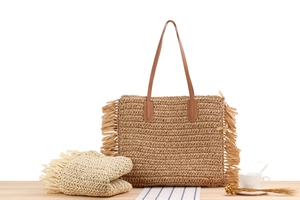 Detail view of straw woven tote bag with long fringe tassels and matching sun hat