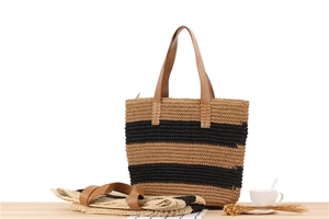 Detail of striped woven tote bag showing its foldable design and leather handles