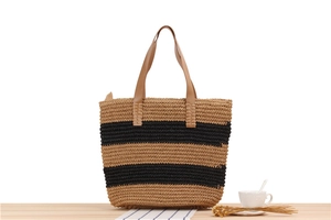 Detail of striped paper rope woven tote bag with premium leather handles on a table