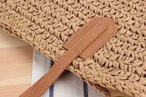 Close-up of woven straw texture and leather strap stitching on casual shoulder bag
