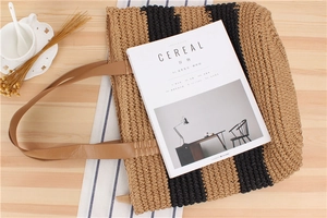 Flat lay of a striped woven paper straw tote bag with brown leather handles and casual decor