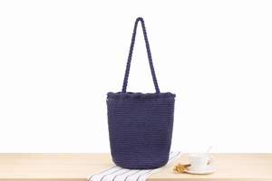 Detailed view of dark purple handmade cotton rope crochet bucket bag on a wooden table