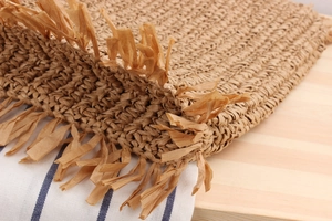 Macro shot of natural paper rope woven bag showing detailed fringe tassels and texture