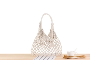 Detailed macro view of bohemian hand-woven macrame cotton rope tote bag with long fringe