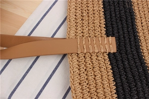 Detail of handwoven striped paper straw bag with reinforced brown leather shoulder strap