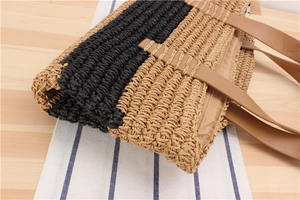 Detail of striped woven paper tote bag featuring brown leather handles and zipper closure