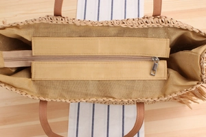 Detail of spacious interior with zipper closure and tan lining for woven straw tote bag