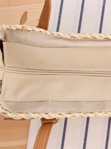 Minimalist straw woven tote bag with brown leather handles and secure zip closure